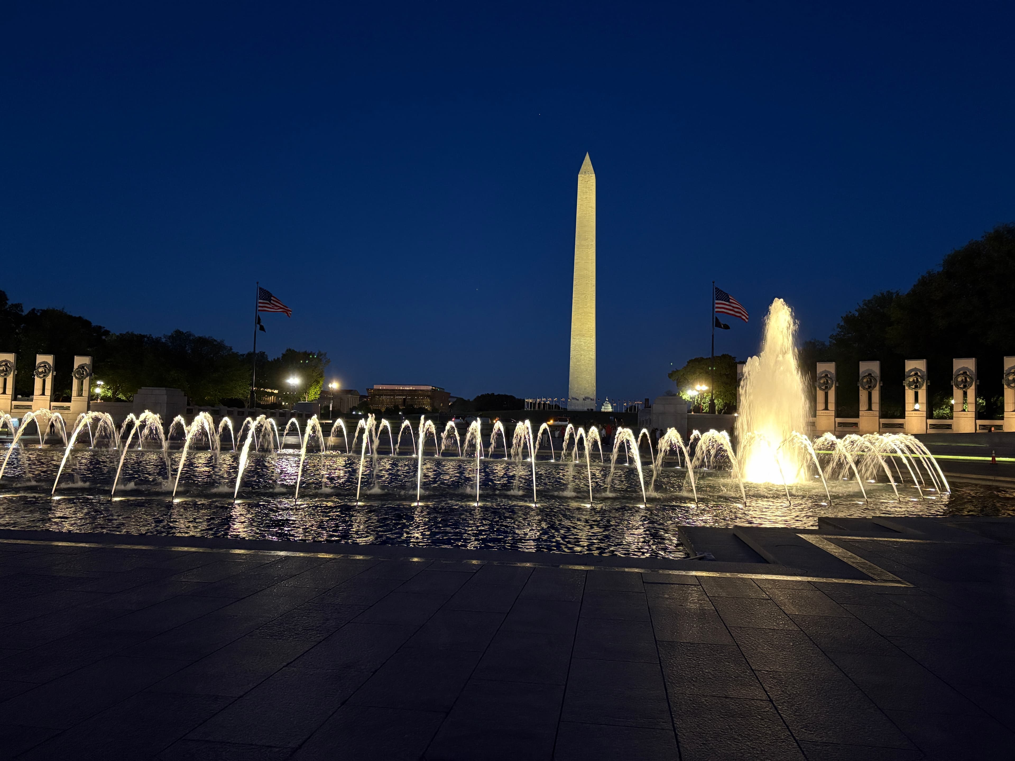 The Washington Monument and World War II Memorial fountains illuminated at night.